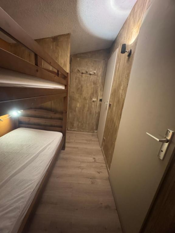 Cette petite chambre comprend un lit et une porte. dans l'établissement Appartement au pied des pistes, à Taninges