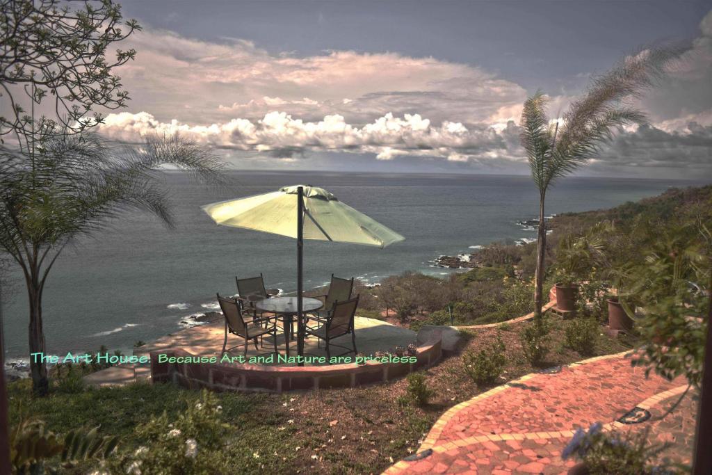 a table and chairs with an umbrella and the ocean at Montezuma Heights in Montezuma