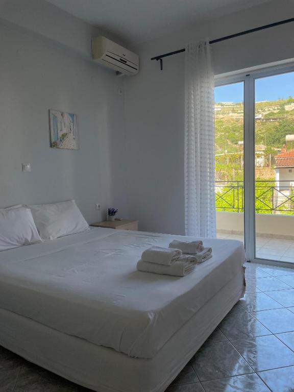 a white bedroom with a bed with towels on it at Marina Apartaments in Himare