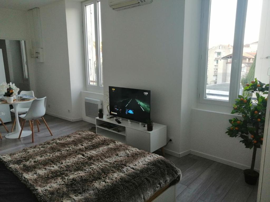 Cette chambre blanche dispose d'une télévision et d'une table avec une chaise. dans l'établissement Latourette VII, à Forcalquier