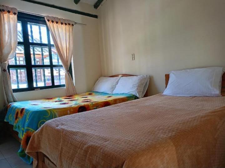a bedroom with two beds and a window at Abi Happy in Villa de Leyva