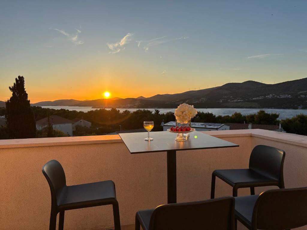a table and chairs on a balcony with a sunset at Villa LeANN in Okrug Donji