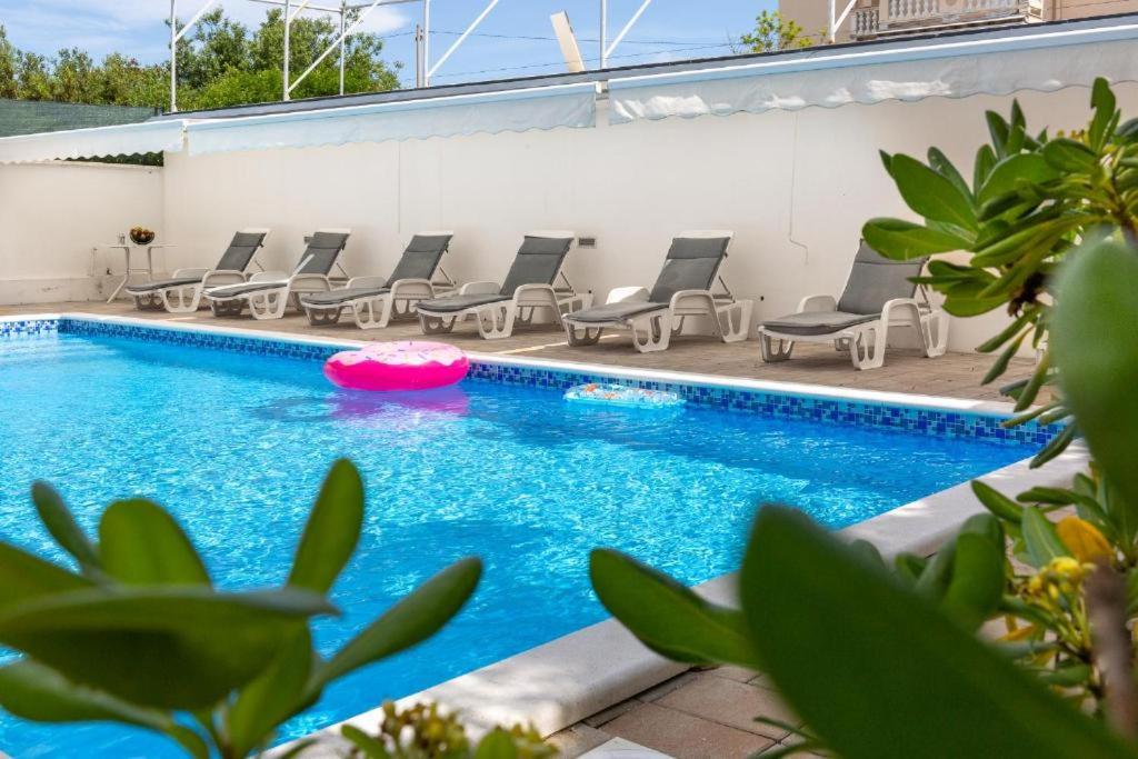a swimming pool with chairs and a pink frisbee in it at Apartments Villa Mirela in Petrcane