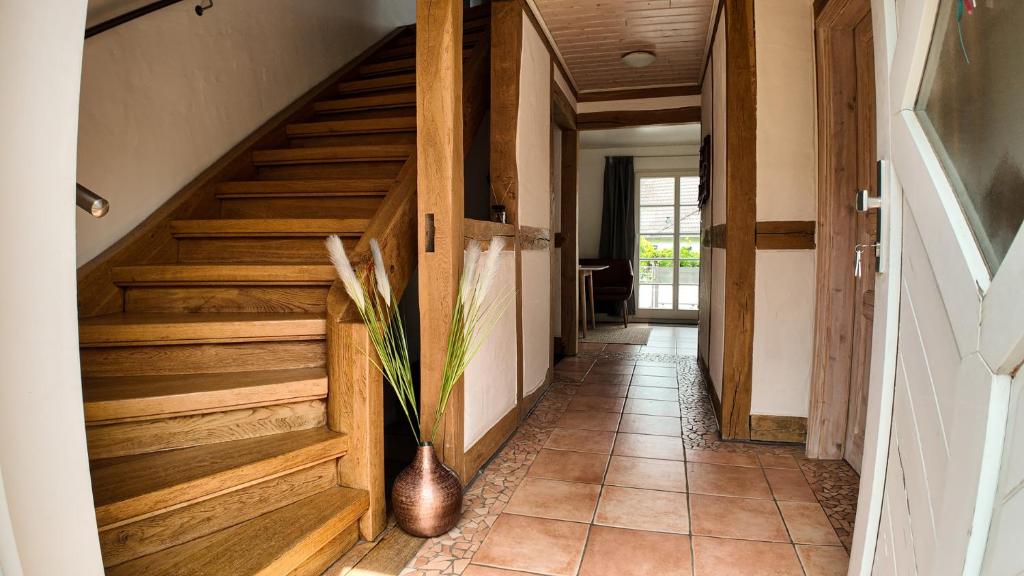 a hallway with wooden stairs and a vase on the floor at Auszeit & Natur - ländliche Fachwerkhaushälfte in Nümbrecht