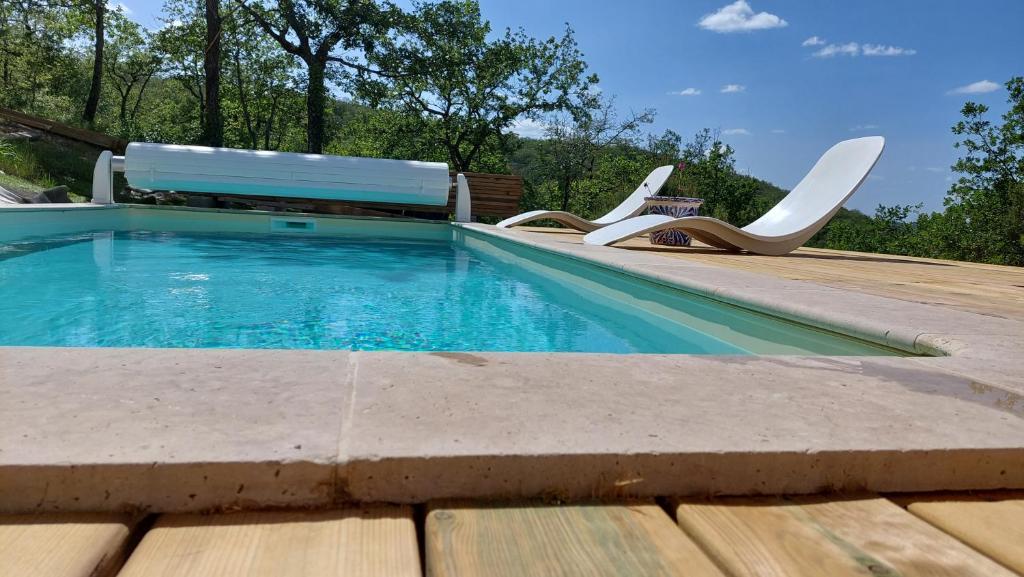 a swimming pool with two chairs and a bench at Notre petit coin de paradis in Saint-Germain-du-Bel-Air
