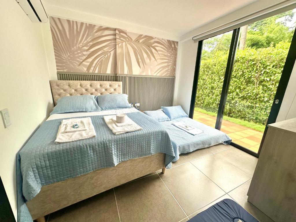 Un dormitorio con una cama con sábanas azules y una ventana. en Cofradia Lodge, en Villavicencio