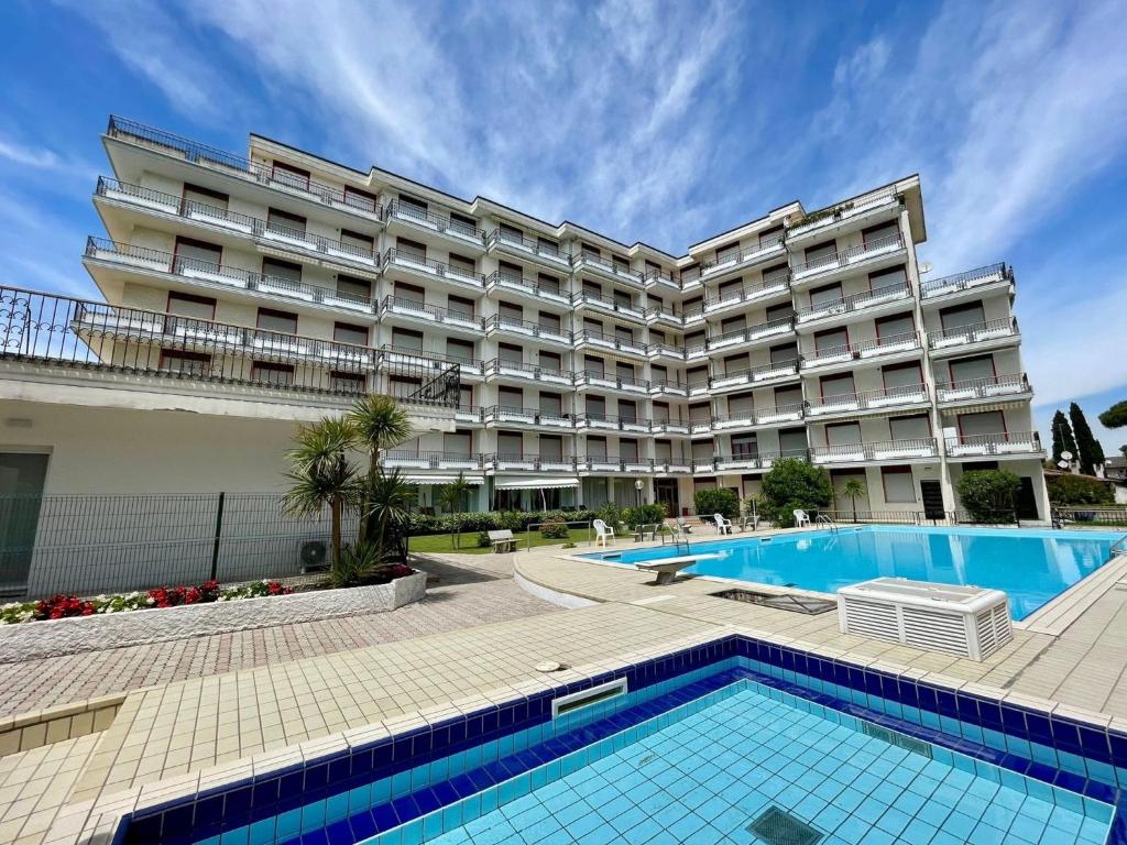 a hotel with a swimming pool in front of a building at Flat in Porto Santa Margherita in Porto Santa Margherita di Caorle