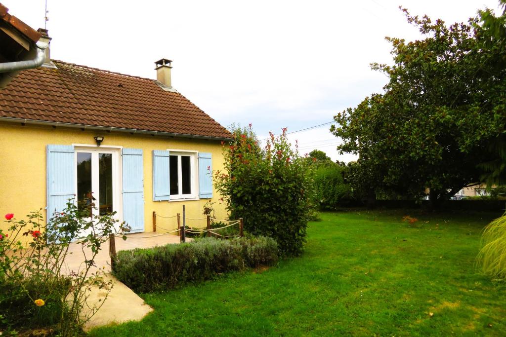 une maison jaune avec une porte bleue et une cour dans l'établissement Le toucan, à La Celle-sous-Gouzon