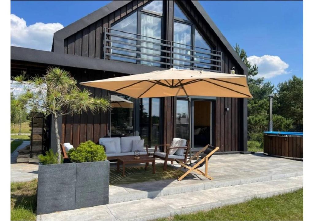 a patio with a table and an umbrella at Nowoczesna stodoła z balią na Mazurach in Trelkowo