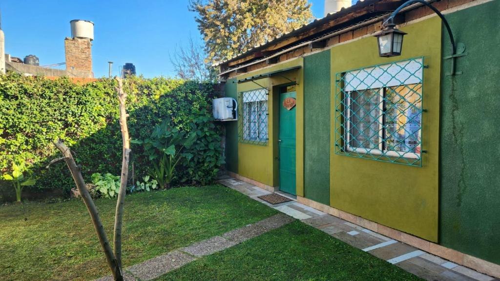 a small green and yellow house with a tree in the yard at Casa 2 ambientes con jardín y garage in Gualeguaychú