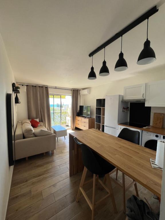 Il comprend une cuisine et un salon avec une grande table en bois. dans l'établissement Appartement proche de la mer, à La Ciotat