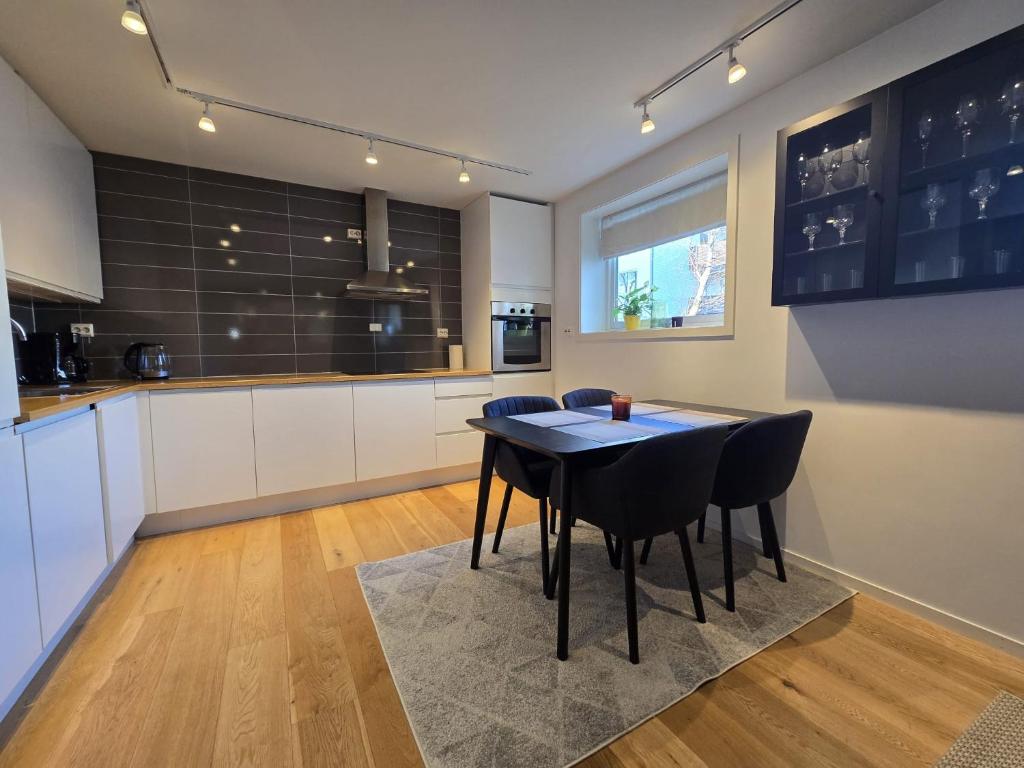 une cuisine avec une table et des chaises dans une pièce dans l'établissement BRUNØST APARTMENT modern apartment close to city center with free parking, à Tromsø