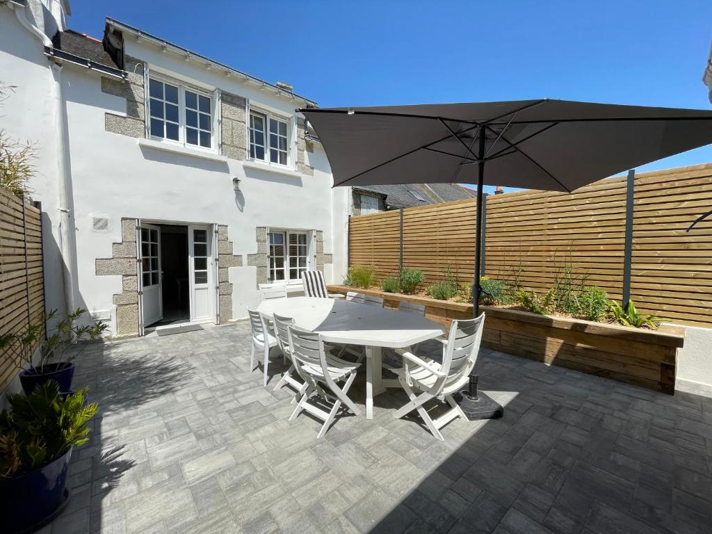 un patio avec une table, des chaises et un parasol dans l'établissement Ty Silin maison de vacances-600m de la plage et 400m du golf de Kerver à pied, à Saint-Gildas-de-Rhuys