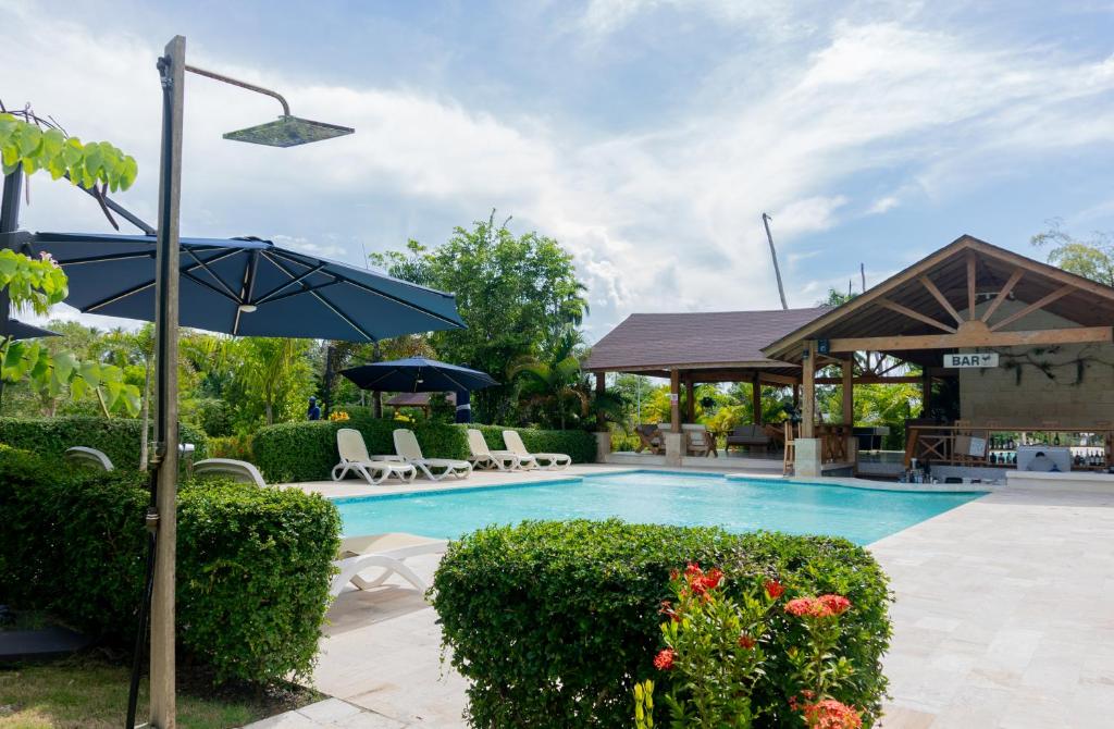 a swimming pool with chairs and an umbrella at Villa Anyelina Hotel boutique in Sánchez