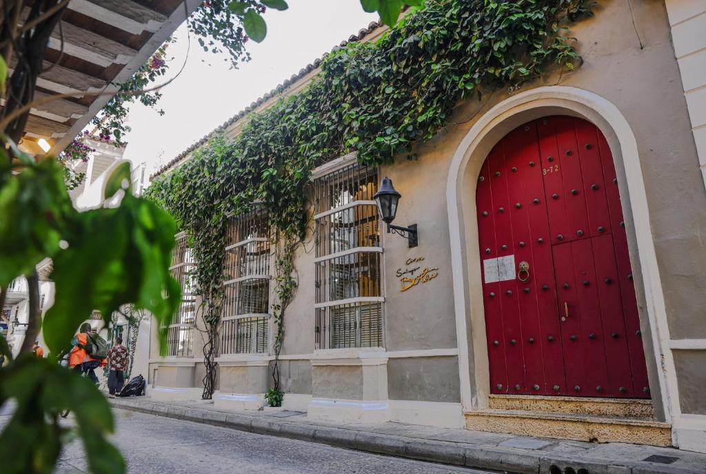 a red door on the side of a building with ivy at Hotel casa santiago botero in Cartagena de Indias