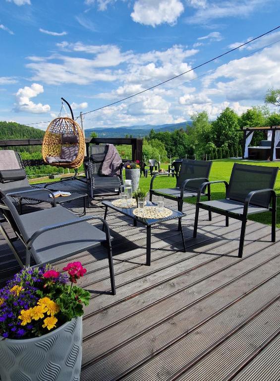 a patio with chairs and tables and flowers on a deck at Domek na Folwarku z jacuzzi in Tarnawa Dolna