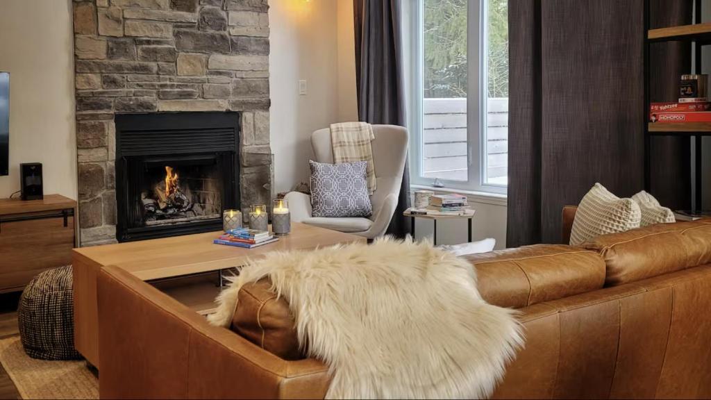 een woonkamer met een bank en een open haard bij Condo cottage-style Tremblant in Saint-Jovite