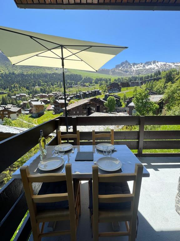 - une table avec des chaises et un parasol sur le balcon dans l'établissement La Casa Di Giuma Magnifique studio à Valmorel, à Valmorel