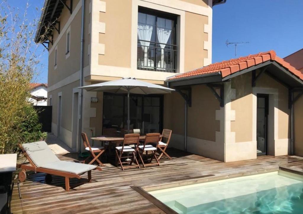 un patio avec une table, des chaises et un parasol dans l'établissement Villa Les Lopins, à Arcachon