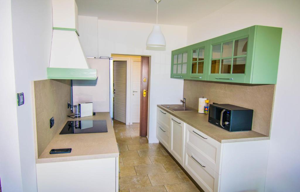 Kuchnia z zielonymi szafkami i kuchenką mikrofalową w obiekcie Apartment Vincent with beautiful sea view terrace w mieście Klenovica