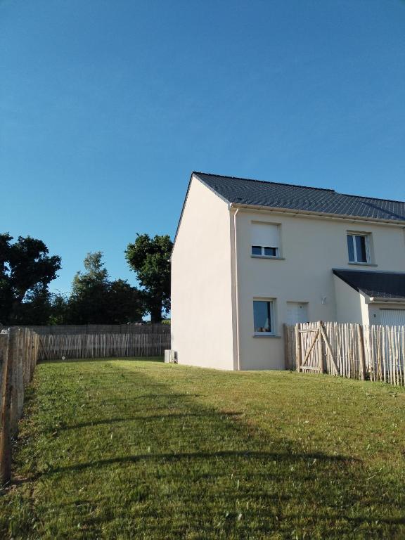 une maison blanche avec une clôture et une cour dans l'établissement Charmante maison neuve au cœur de Matignon, à Matignon