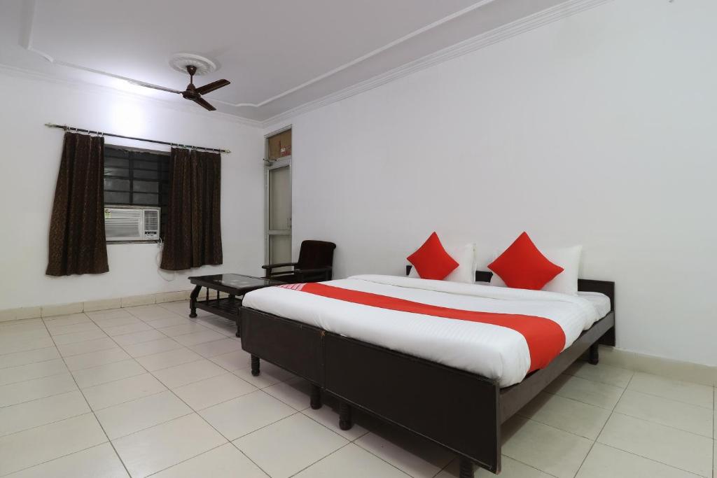 une chambre avec un lit avec des oreillers rouges et un bureau dans l'établissement Hotel O Shri Tirupati, à Nalmatha