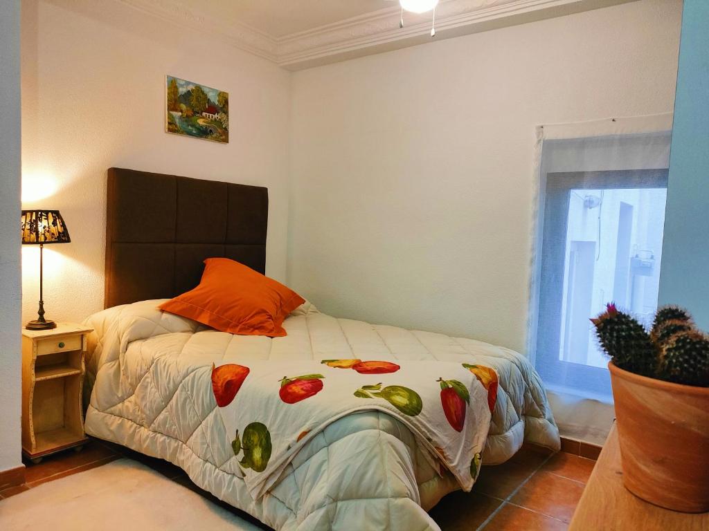 Un dormitorio con una cama con una almohada naranja y una ventana en Estudio El Santo 2, en Salamanca