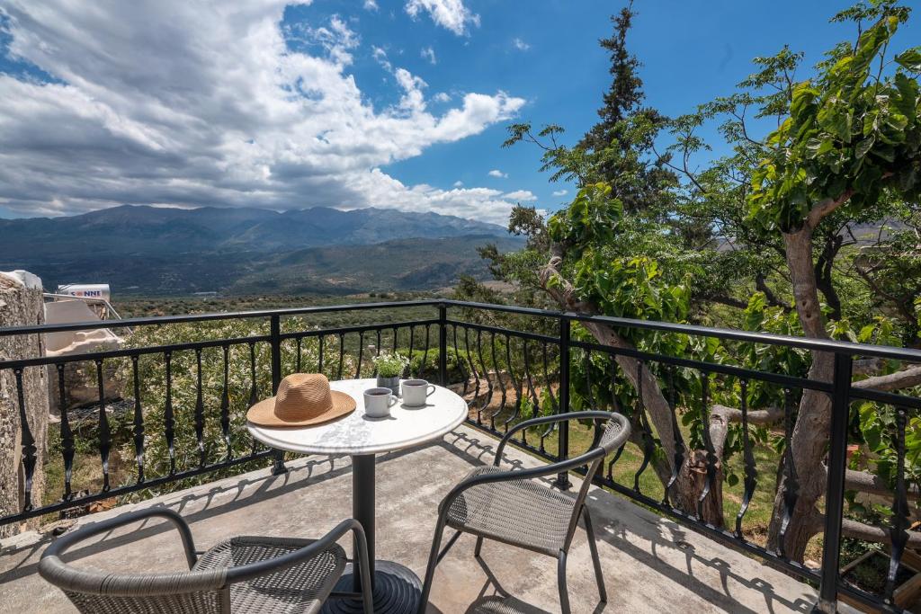 a table and chairs on a balcony with mountains at Aptera Verde - Stone Cottages Complex in Áptera