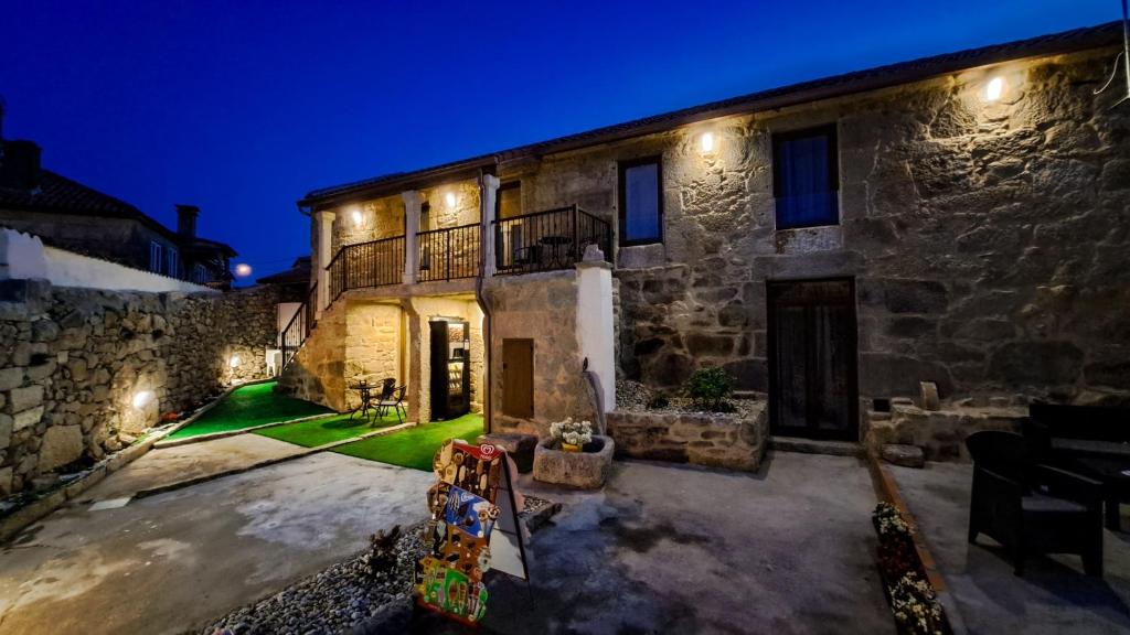 Santa MaríaAlbergue Turistico En Armenteira A Fragua do Ferreiro的石头房子,晚上有院子