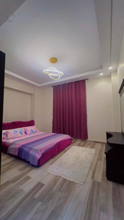 a bedroom with a bed and a red curtain at Hotel apartment at sheikh zayed city in Sheikh Zayed