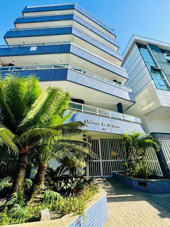 a large building with palm trees in front of it at Ap prainha top in Arraial do Cabo