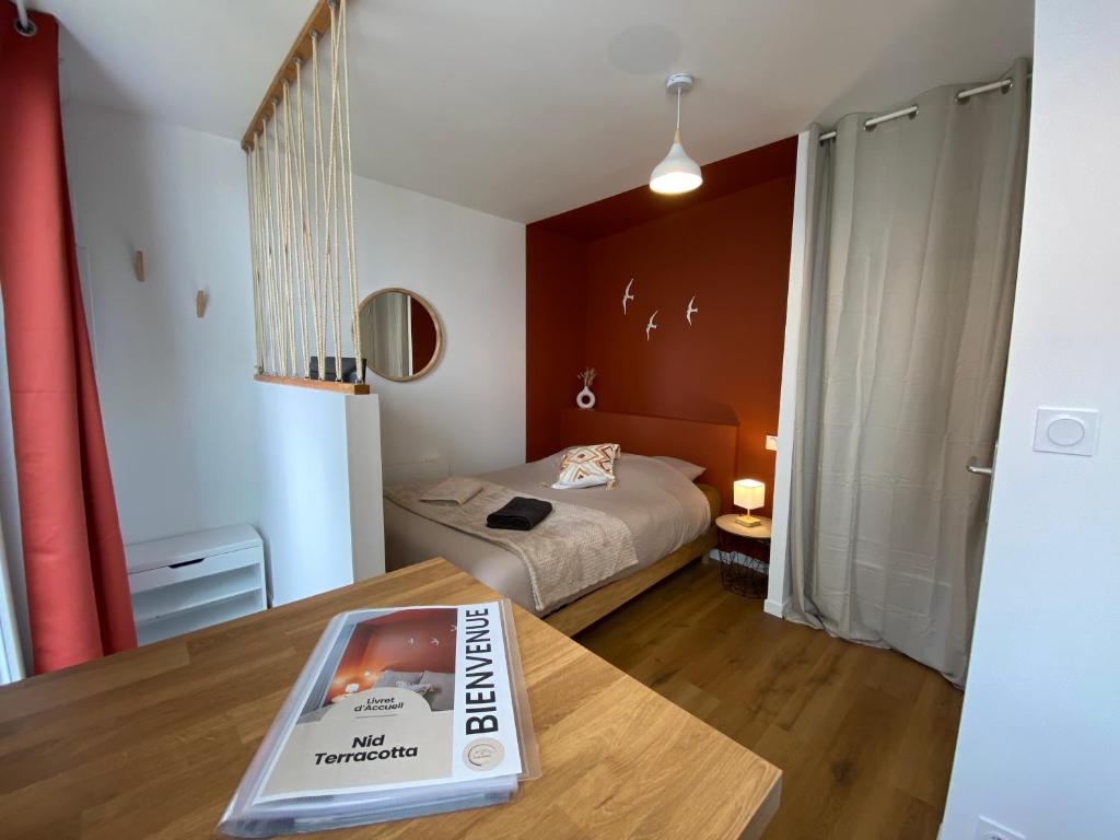 a room with a bed and a table with a book at Le Nid Terracotta Charme et Sérénité à Saint-Brieuc in Saint-Brieuc