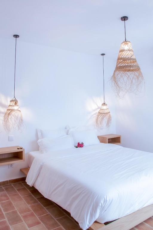 a bedroom with a white bed with two pendant lights at Mar-Ria 4 in Fuzeta