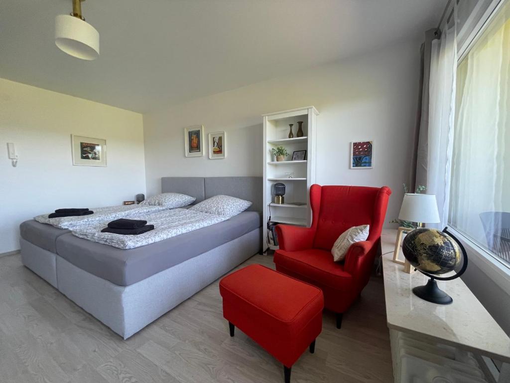 a bedroom with a bed and a red chair at Loreleyblick-Ferienwohnung am Rheinsteig - Natur und Aussicht in Patersberg