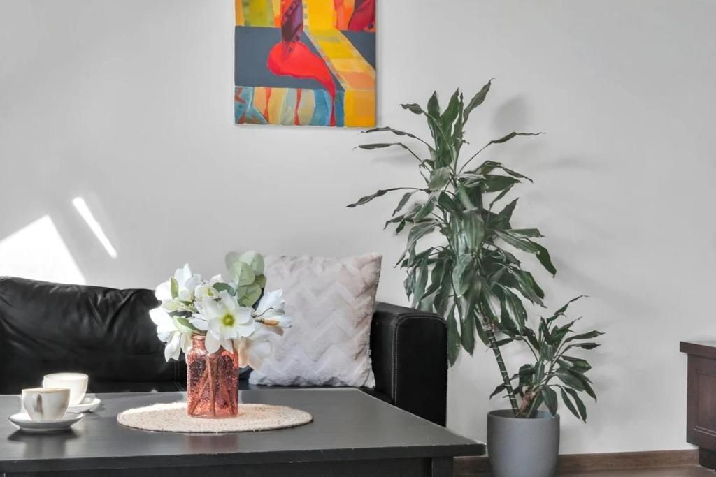 Una sala de estar con una mesa con flores y un sofá. en Vilnius Old Town Amber Penthouse, en Vilna