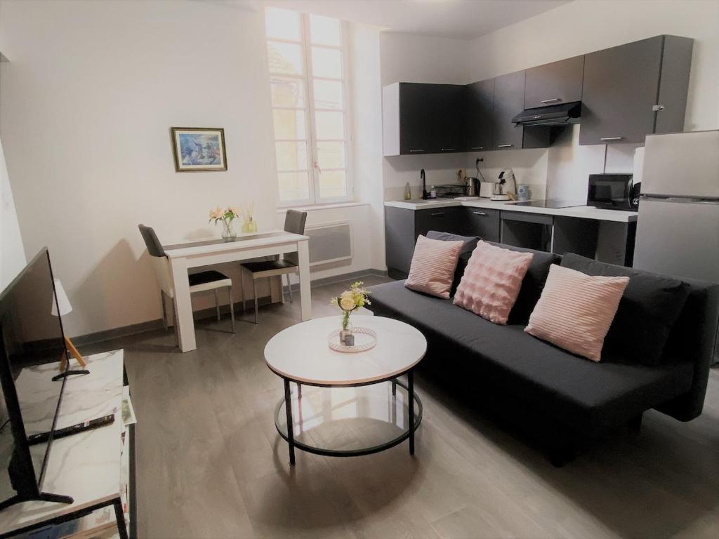 a living room with a black couch and a table at 2 pièces élégant calme central parking sur place in Foix