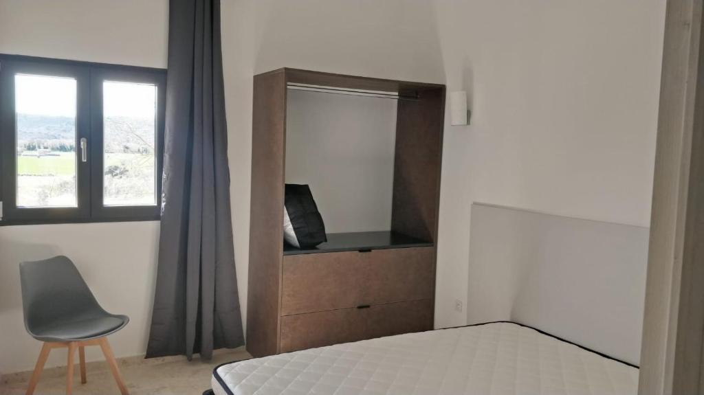 une chambre avec un lit, une chaise et une fenêtre dans l'établissement Résidence Bastide Blanche, à La Celle-sous-Gouzon