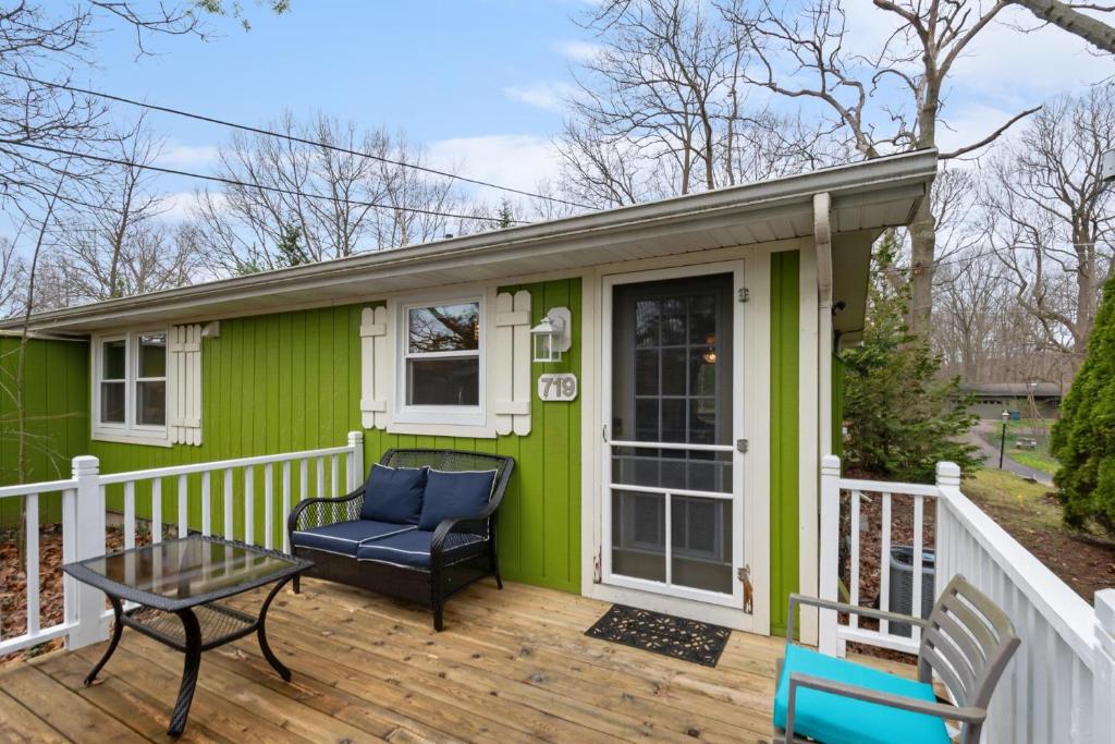 a green house with a chair and a table on a deck at Cozy Cottages Green Cottage Hot tub-Town in Saugatuck