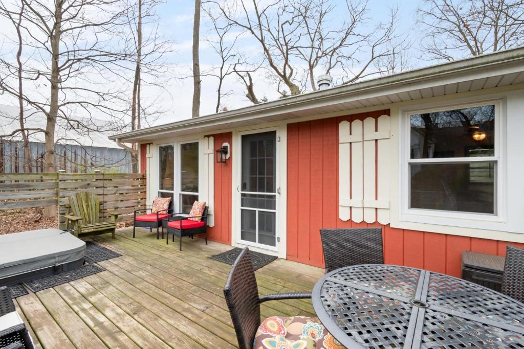 a deck with a table and chairs on a house at Cozy Cottages Red Cottage Hot tubTown in Saugatuck