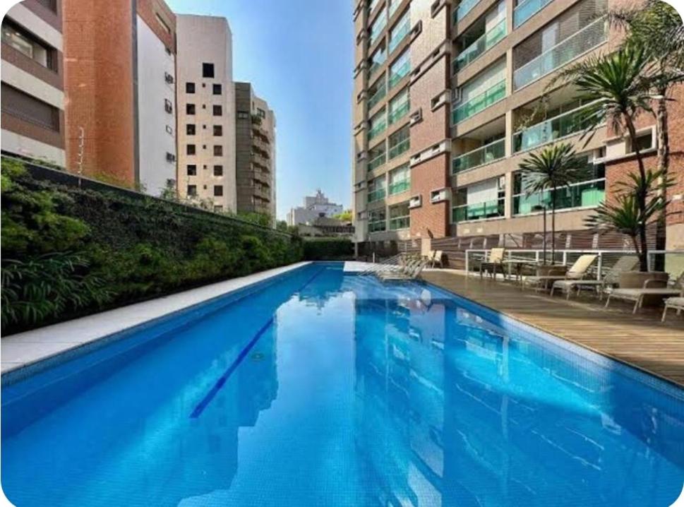圣保罗Flat in Mada with pool的一座大型蓝色游泳池,位于部分建筑前