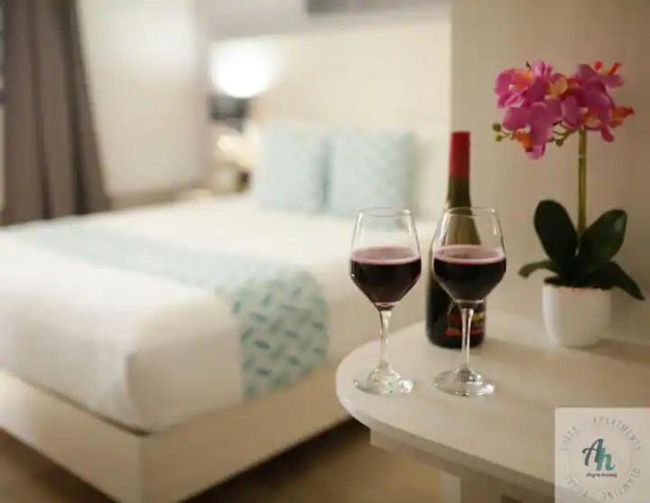 zwei Gläser Wein auf einem Tisch neben einem Bett in der Unterkunft B - Céntrico Loft Privado - Alegría Housing in Aguascalientes