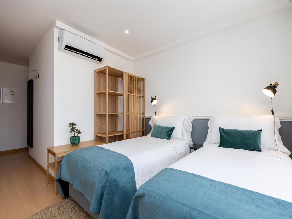 a bedroom with two beds and a book shelf at Feel Corporate Housing Marquês Garden View in Porto