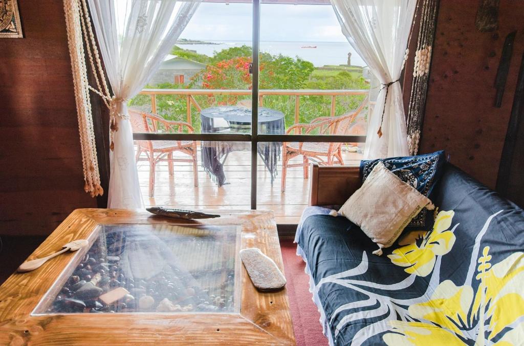 a living room with a couch and a large window at Cabañas Moai in Hanga Roa