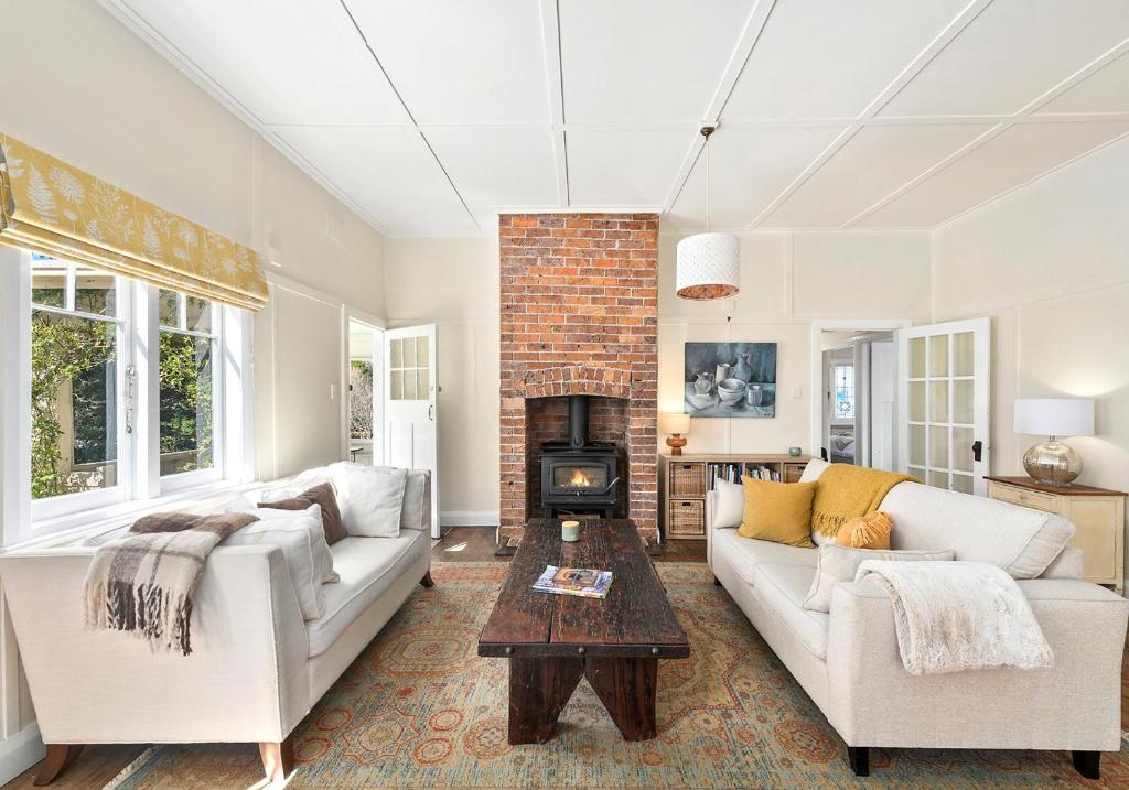 un soggiorno con divano e camino di Country Cottage Charm a Mittagong