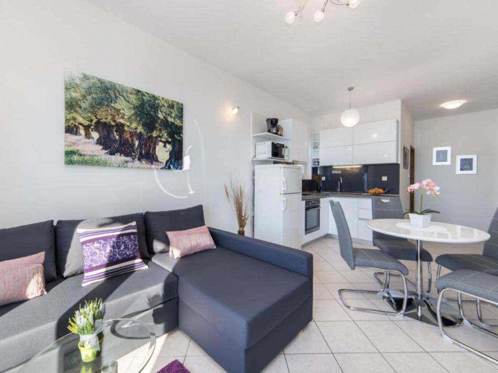 a living room with a blue couch and a kitchen at Apartments Tafra - One Bedroom Apartment in Lokva Rogoznica