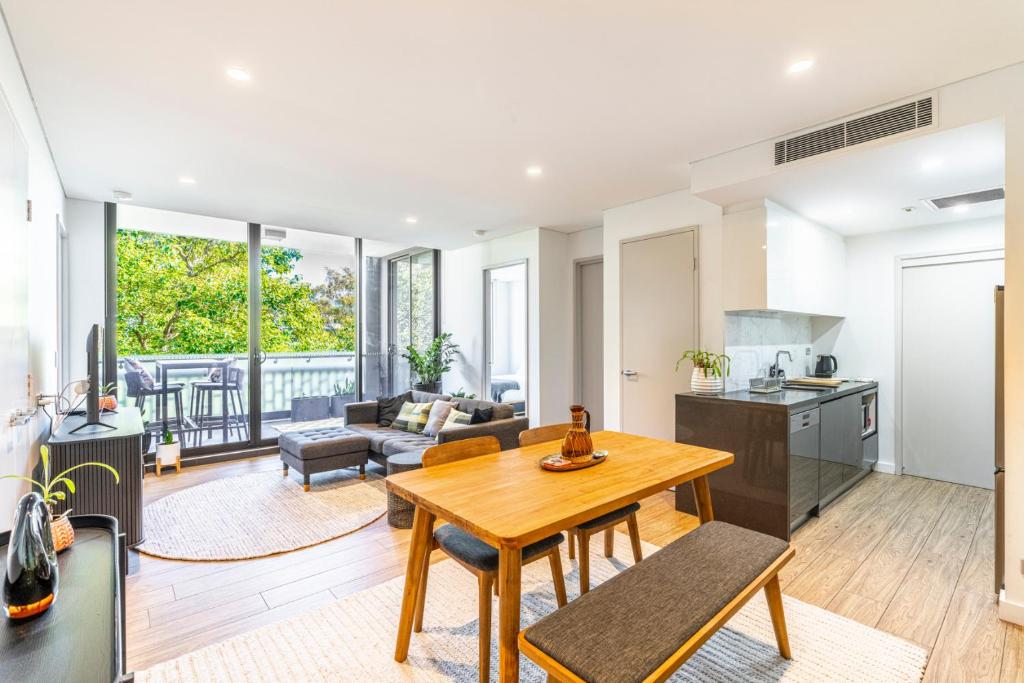 a kitchen and living room with a wooden table at Waterloo 2BR Getaway with Pool & Gym Access in Sydney