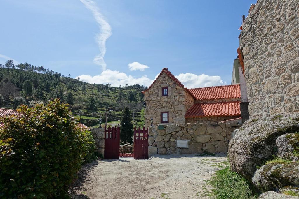 a stone house with a red roof and a stone wall at Casas da Fonte - Serra da Estrela in Seia