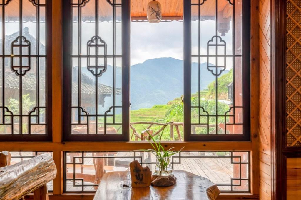 a room with a window with a view of a mountain at Longsheng Longji Rice Terraces Jingyue Hotel 龙胜龙脊梯田境悦酒店 in Longsheng