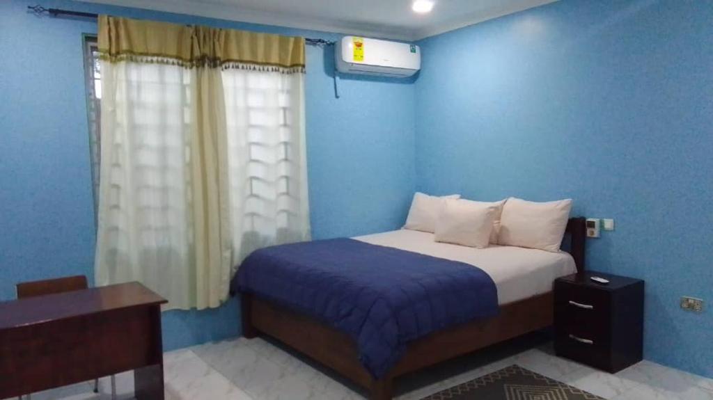 a blue bedroom with a bed and a window at K-Rose Guesthouse and Travel Lodge in Accra