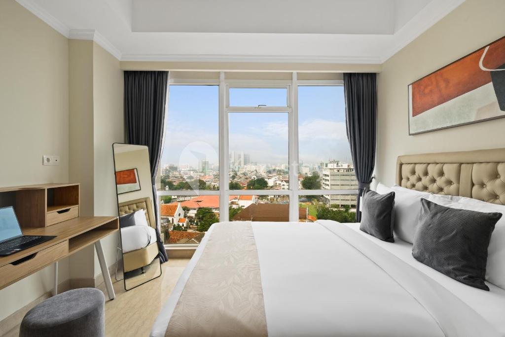 a hotel room with a bed and a large window at Alden by Kozystay - Menteng in Jakarta